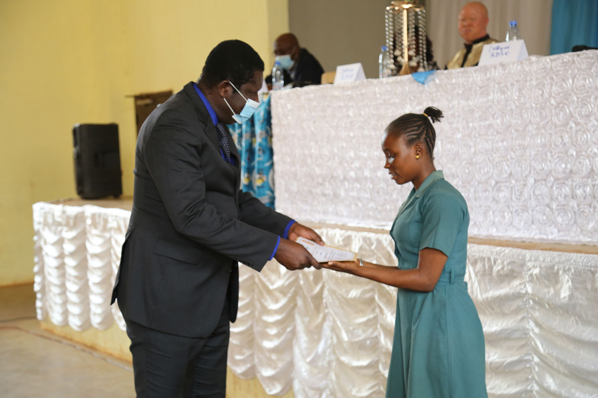 Dr. Ngabnya hands an award to a visually impaired student
