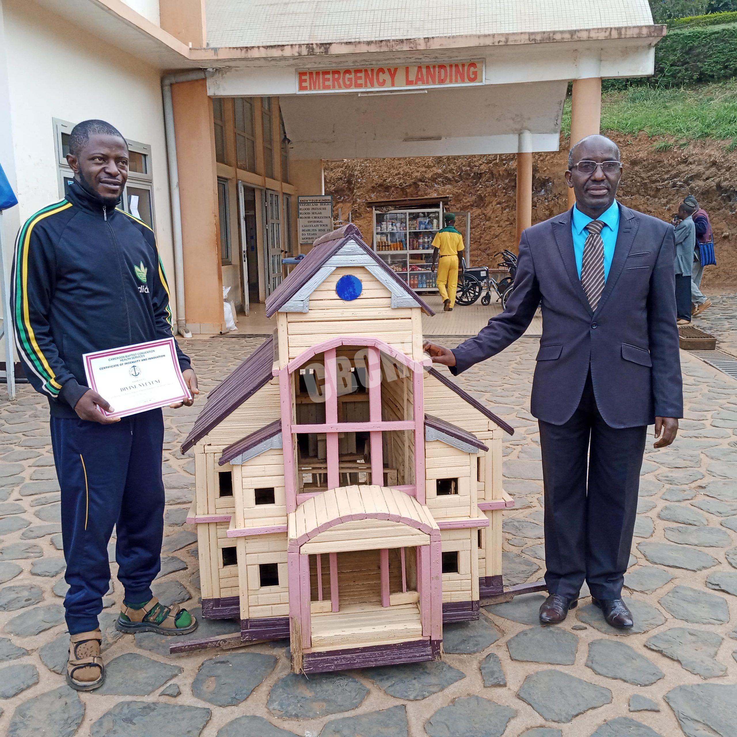 BBH Senior Administrator, Mr. Nji Richard poses with craft work of BBH OPD & the artist, Divine Nyuyyuni
